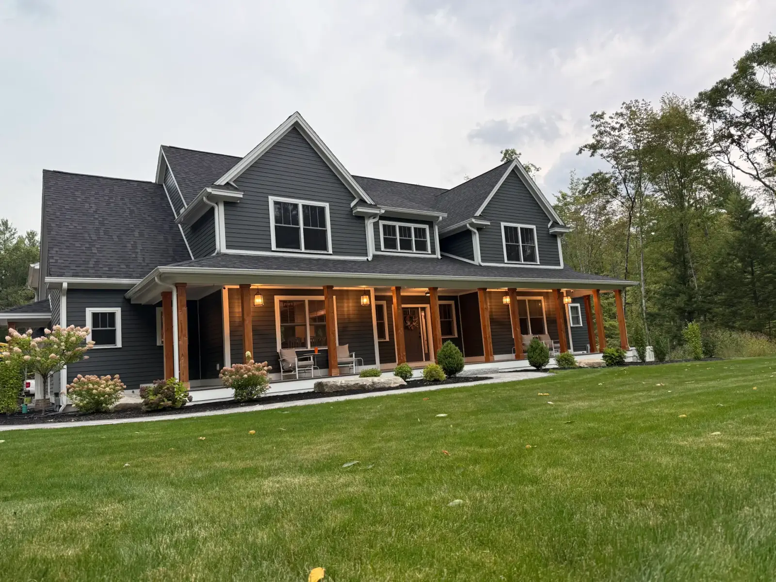Dark-sided custom New England home with a covered timber porch